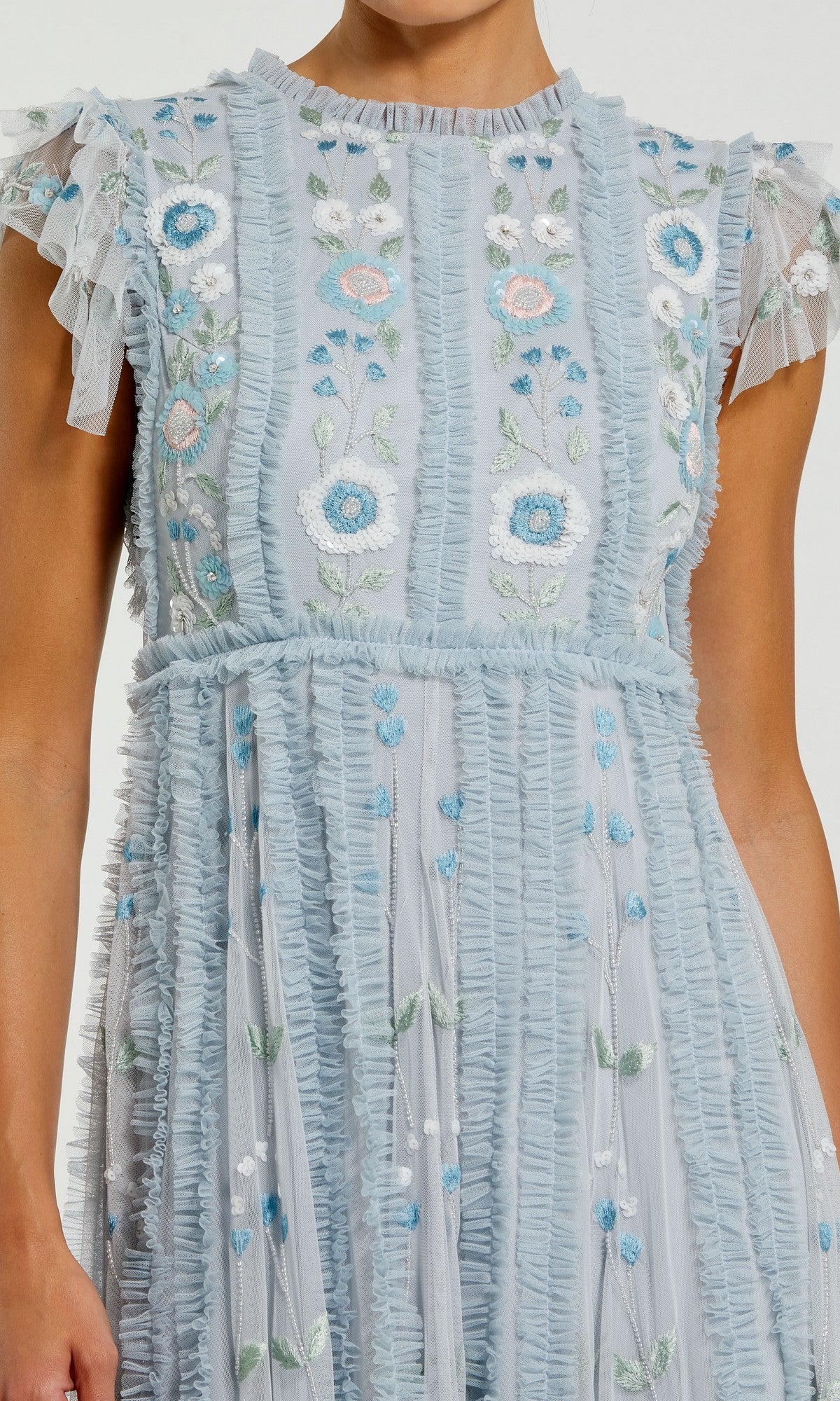 A person wearing the Mac Duggal 9366 long formal dress in light blue, featuring ruffled details and delicate floral embroidery in white, blue, green, and pink on an elegant A-line skirt.